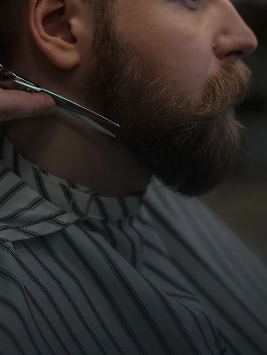 Diseño de barba masculina con tijera en barbería