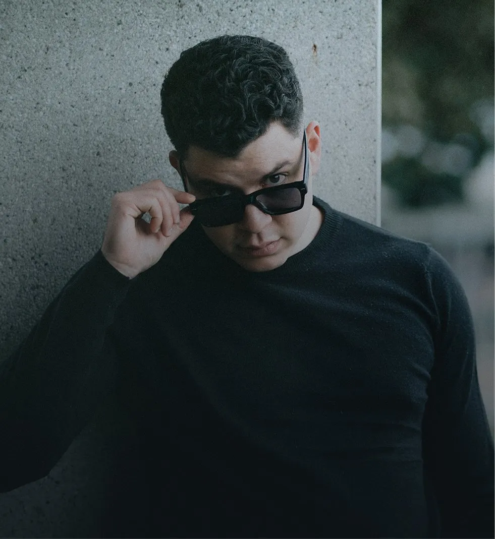 Andrés Miranda con gafas de sol junto a un muro de concreto