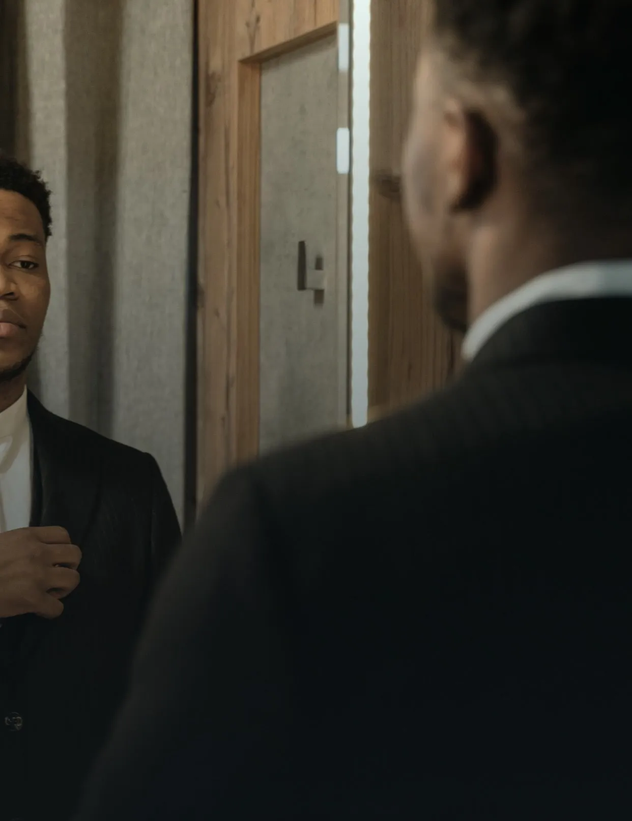 Hombre de traje observando su reflejo en el espejo, asesoría de imagen masculina